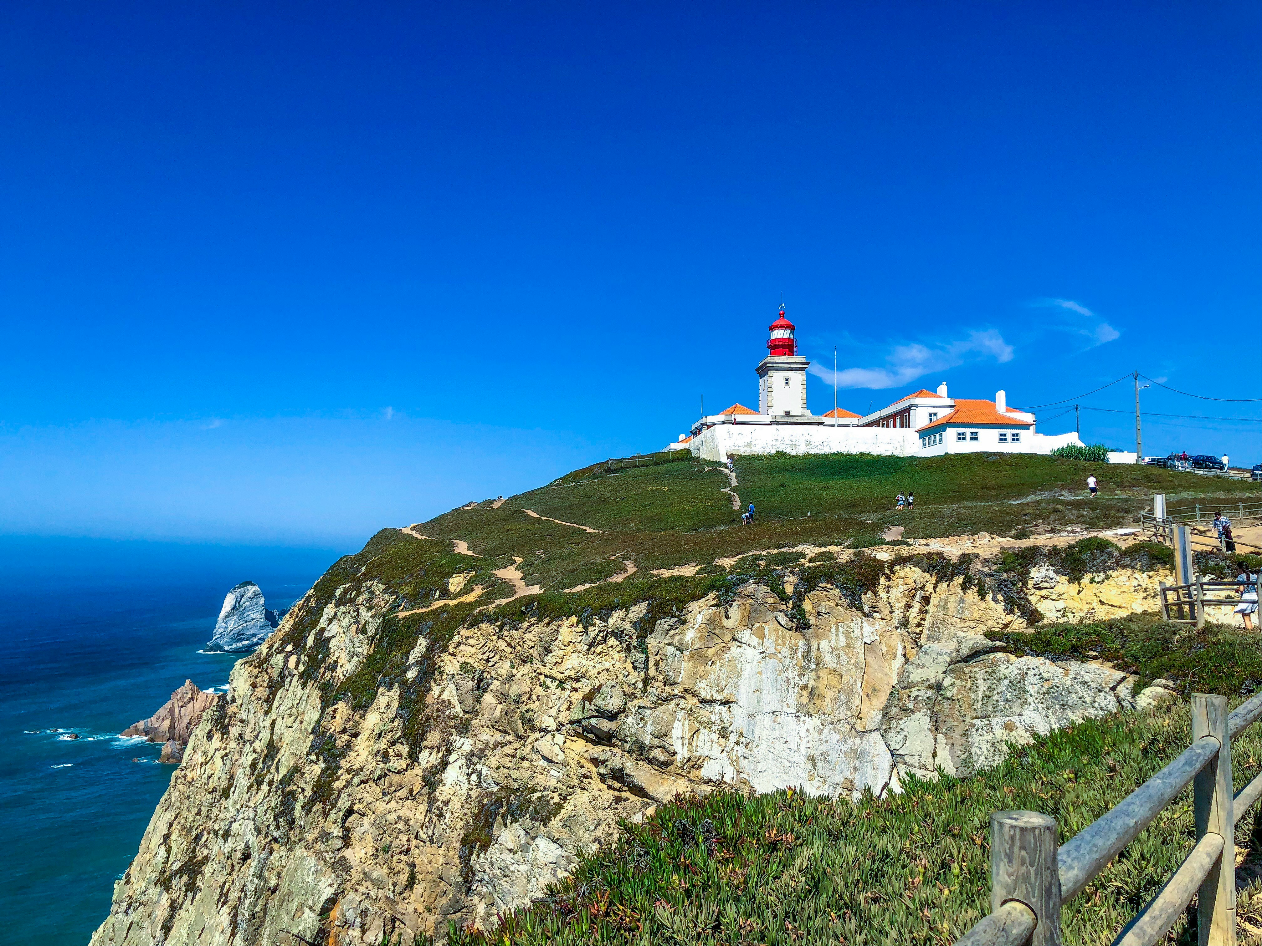 lighthouse on mountain near body of water